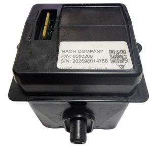 Black plastic electronic module with a cylindrical outlet at the bottom, mounted on a base; label reads Hach Company P/N 8560200 and S/N 202698014758.